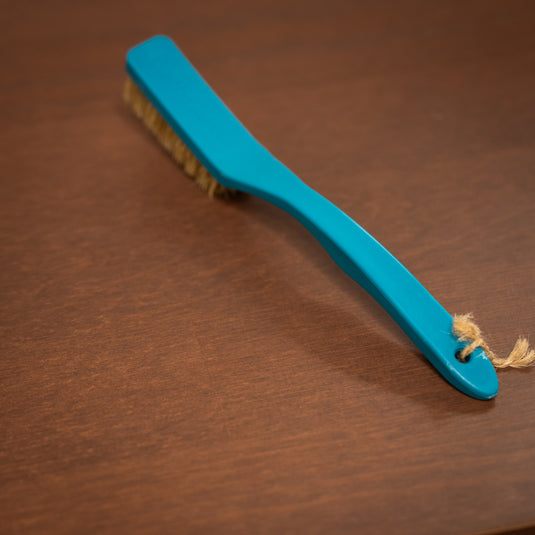 8b+ save the ocean climbing brush in blue resting on a wooden surface displaying hole at the end of the brush allowing attachment options.