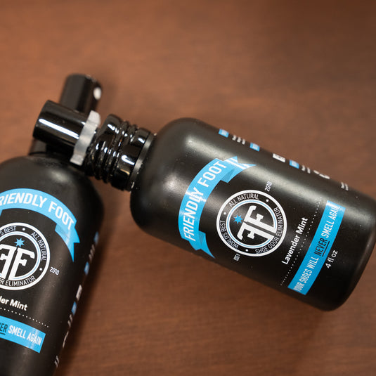 two friendly foot sprays. in black spray bottle with blue and white design laid on wooden surface