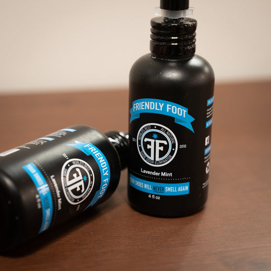 two friendly foot sprays. in black spray bottle with blue and white design laid on wooden surface