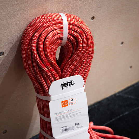 Petzl Arial climbing rope 9.5mm in reddish orange, coiled up in white packaging.