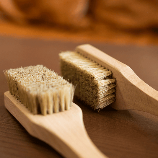 Two wooden Beta climbing brushes engraved with Beta Climbing Designs logo. Resting on wooden surface showcasing the horse hair bristles