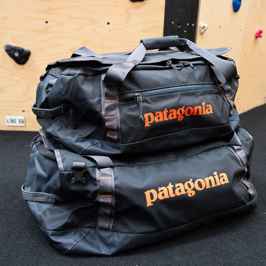 Two Patagonia Black Hole Duffels, one 40l and one 55l stacked on top of one another with climbing wall in background