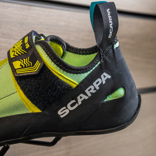 A close up of Scarpa Origin VS women heel, resting on black hook against metallic background.