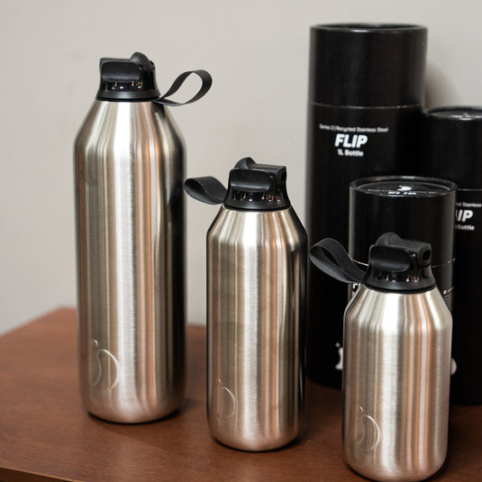 3 stainless steel bottles in different sizes displayed on wooden surface all with a black flip top straw lid. 1L, 500ml and 350ml.