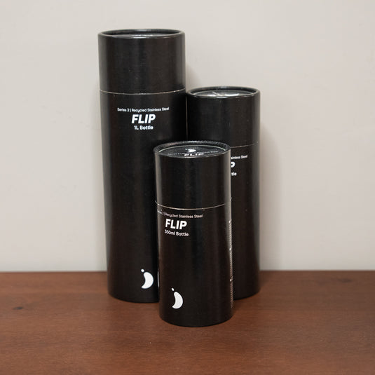 three cylindrical black packaging with Series 2 - Recycled Stainless Steel Flip Bottle text and Chillys logo in white