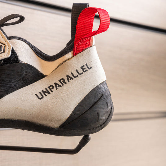 A close up of Unparallel Qubit heel, resting on black hook against metallic background.