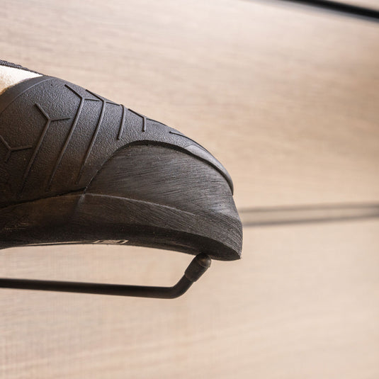 A close up Unparallel Qubit toe box, resting on black wall hook against metallic background.