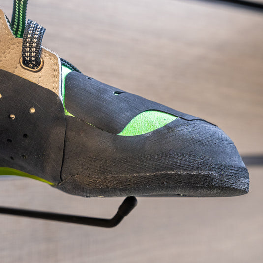 A close up Tenaya Mundaka toe box, resting on black wall hook against metallic background.