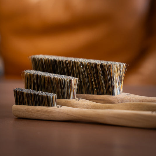 Three Silly Goat brushes showcasing the boar hair bristles and different sizes resting on wooden surface.