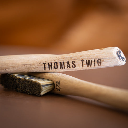 Two Thomas Twig Silly Goat brushes resting on wooden surface. Thomas Twig engraved on the handle and brush ID number 872