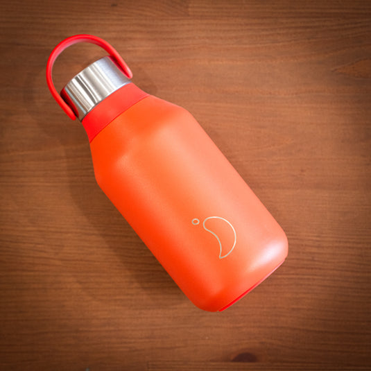 Red 350ml chilly's water bottle with stainless steel lid displayed on wooden surface lay down