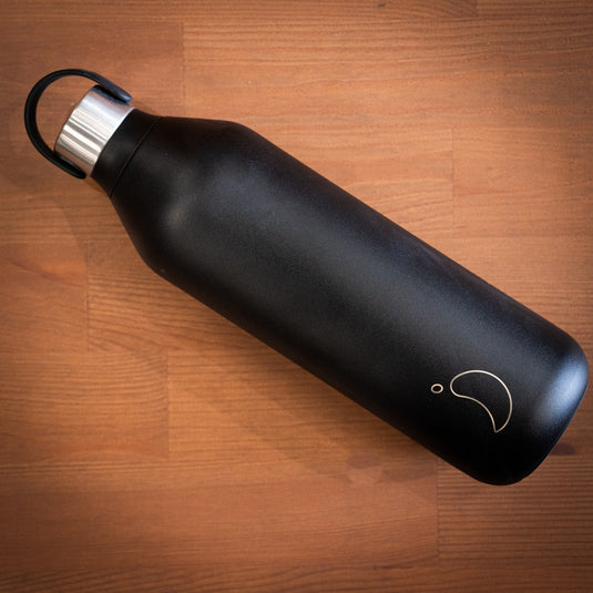 Black 1l chilly's water bottle with stainless steel lid displayed on wooden surface lay down