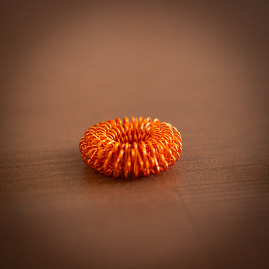 Bright Orange ClimbSkin finger massager resting on wooden table.