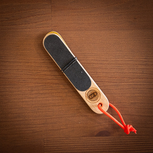 Wooden hand file with black paper, orange cord loop. Laid on wooden surface.