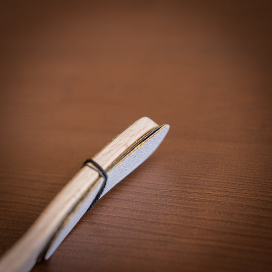 Wooden hand file with replacement papers attached to file via rubber band. Laid on wooden surface.