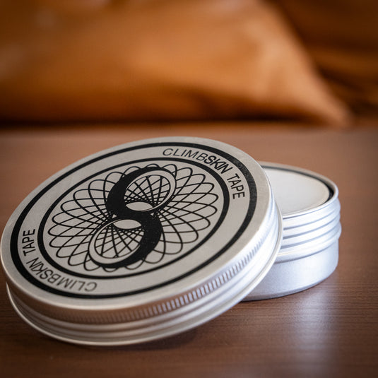 Circular Metal Tin with ClimbSkin Tape logo on the lid. Displayed on wooden surface.