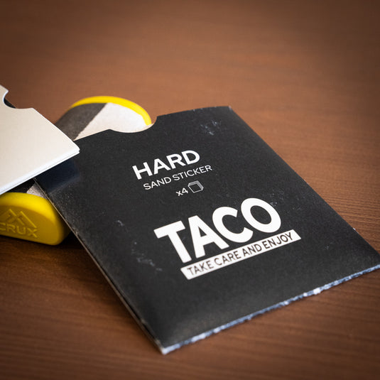 Yellow Crux Skin File laid on wooden surface with replacement hard papers in black packet.