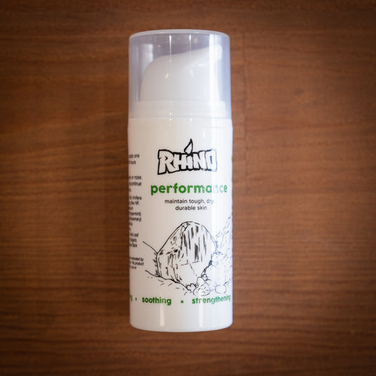 Smaller pump bottle of Rhino Skin Performance - maintain tough, dry durable skin. White and green design, displayed on wooden surface.