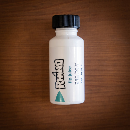 Small brush on container of Rhino tip juice - toughen fingertips for hard crimping laid down on wooden surface