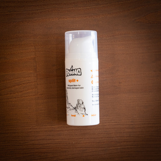 One bottle of Rhino split+ whipped balm for extremely damaged skin, laid on a wooden surface.