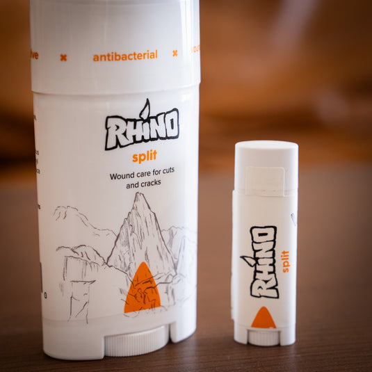 Two containers bottle of Rhino split wound care for cuts and cracks on a wooden surface. One large and one lip-tube sized.