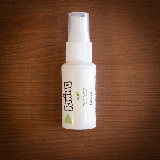 Smallest spray bottle of Rhino Spit - hydrating spray for dry hands. Displayed on wooden surface.