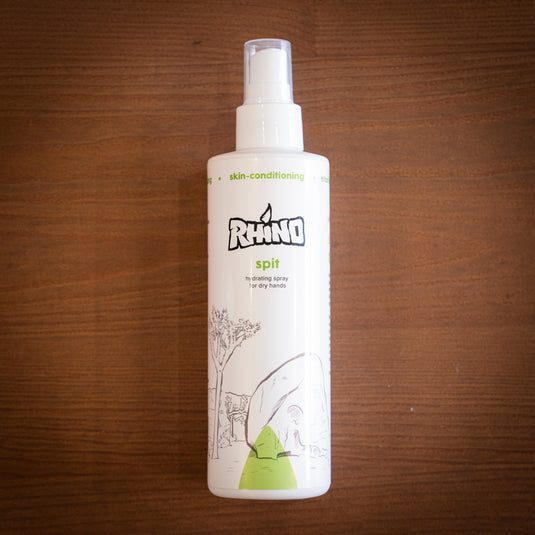 Large spray bottle of Rhino Spit - hydrating spray for dry hands. Displayed on wooden surface.