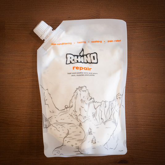 Large refill pouch of Rhino Skin Repair - heal and soothe sore and worn skin. In red and white design laid on wooden surface.