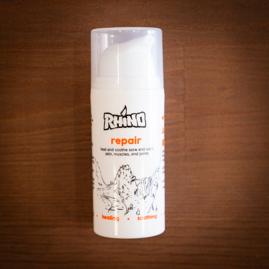 Small pump bottle of Rhino Skin Repair - heal and soothe sore and worn skin. In red and white design laid on wooden surface.