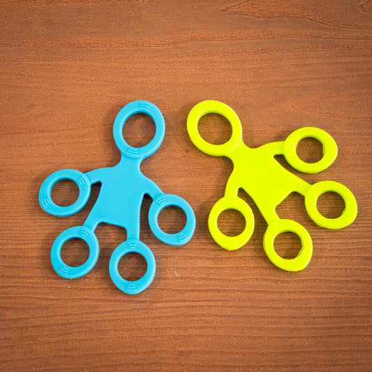 Two finger trainers in green and blue shaped like five inter-connected circles, resting on wooden surface.