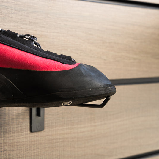 A close up Unparallel Up lace LV toe box, resting on black wall hook against metallic background.