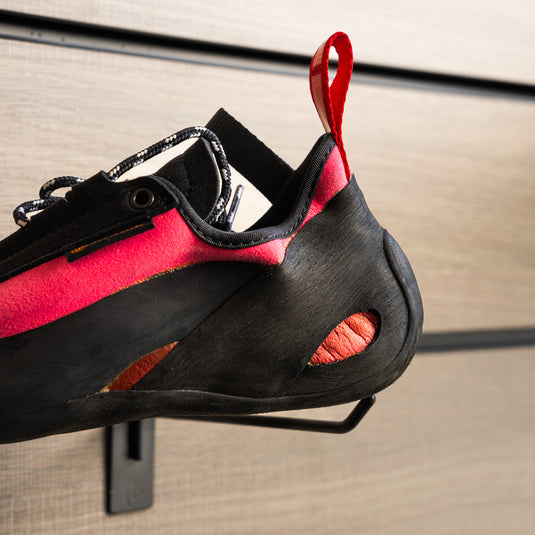 A close up Unparallel Up lace lv Heel, resting on black wall hook against metallic background.