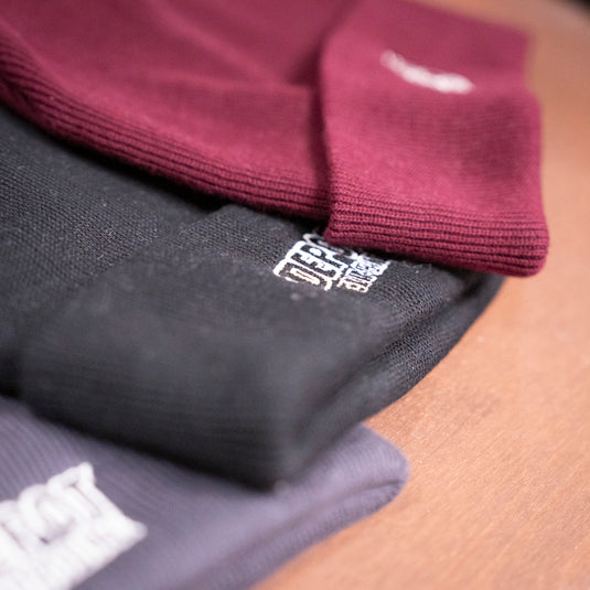 Depot Beanie in various colours laid on wooden surface
