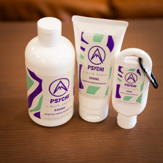 Three containers of Psychi Liquid chalk, 250ml bottle, 100ml tube and a 50ml tube with a black carabiner. All labeled with purple and green designs.