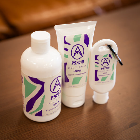 Three containers of Psychi Liquid chalk, 250ml bottle, 100ml tube and a 50ml tube with a black carabiner. All labeled with purple and green designs.