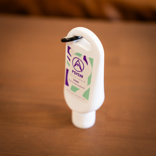 Side Profile of Psychi Liquid chalk, 50ml tube with a black carabiner with purple and green design.