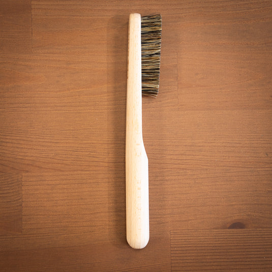 One wooden Climb Lab brush resting on a wooden surface