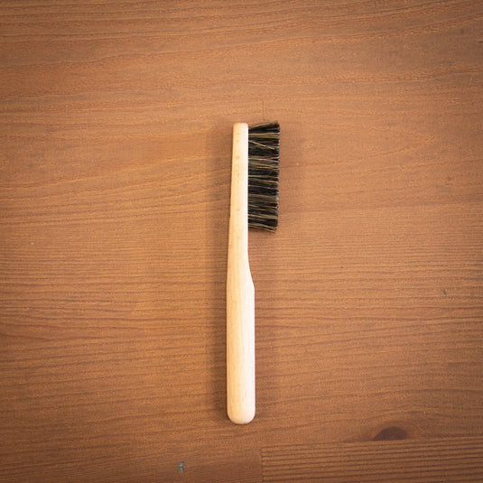 One wooden Climb Lab brush resting on a wooden surface