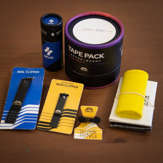 Various hand care items on wooden surface: Nail Clippers, Skin Clippers, Finger Massage Ring, Tape Pack, Repair Stick and a Yellow Skin File