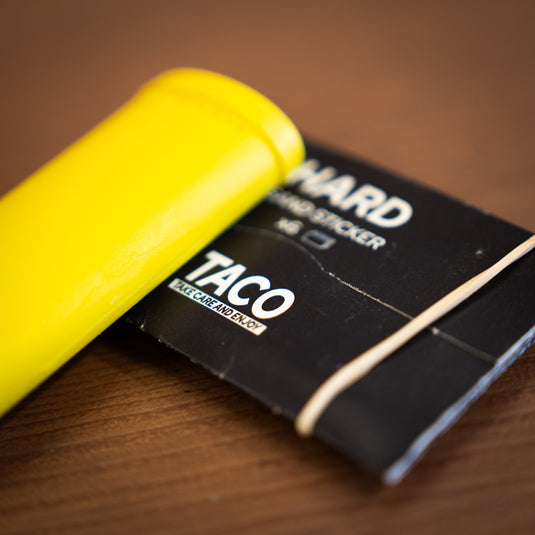 Close up of the Crux Skin File in yellow. Displayed laid down on wooden surface with replacement papers in black packet.