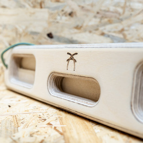 A wooden ash hangboard with various cutouts in the centre.