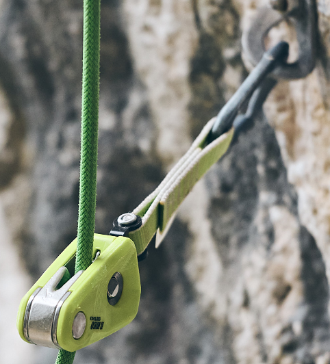 Edelrid OHM II in lime green, clipped into a bolt on a rockface with green rope going through device