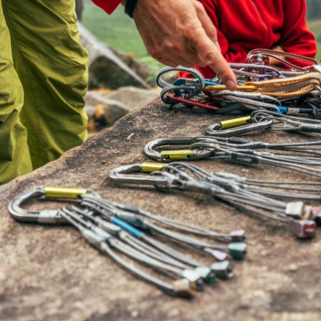 PERFECTO CARABINER IN USE AT A CRAG WITH MULTIPLE AND VARIOUS GEAR ATTACHED. LAID ON ROCK SURFACE.