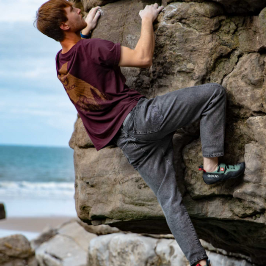 3rd Rock Gaia Jens in Ink Black worn by model climbing boulder at the seasid