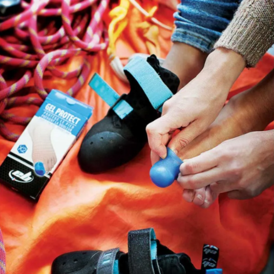 Climber putting on EB gel toe protector with climbing shoes and rope in background