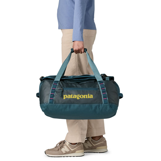 Black Hole Duffel 40L in Tidal Teal w/Luminous Pink being carried by model