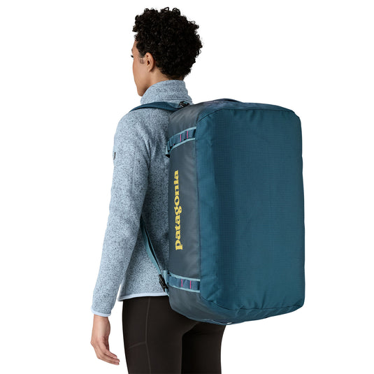 Black Hole Duffel 55L in Tidal Teal w/Luminous Pink being carried by model