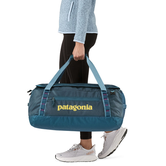Black Hole Duffel 55L in Tidal Teal w/Luminous Pink being carried by model