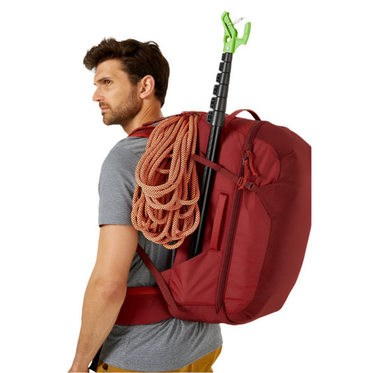 Rab Outcast 44l in red on mans back with rope and clipstick attached