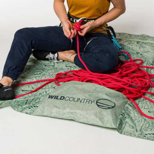 Gearstorm Rope Tarp by Wild Country - shown with rope in pocket and climber sat on tarp tying in to end of the rope